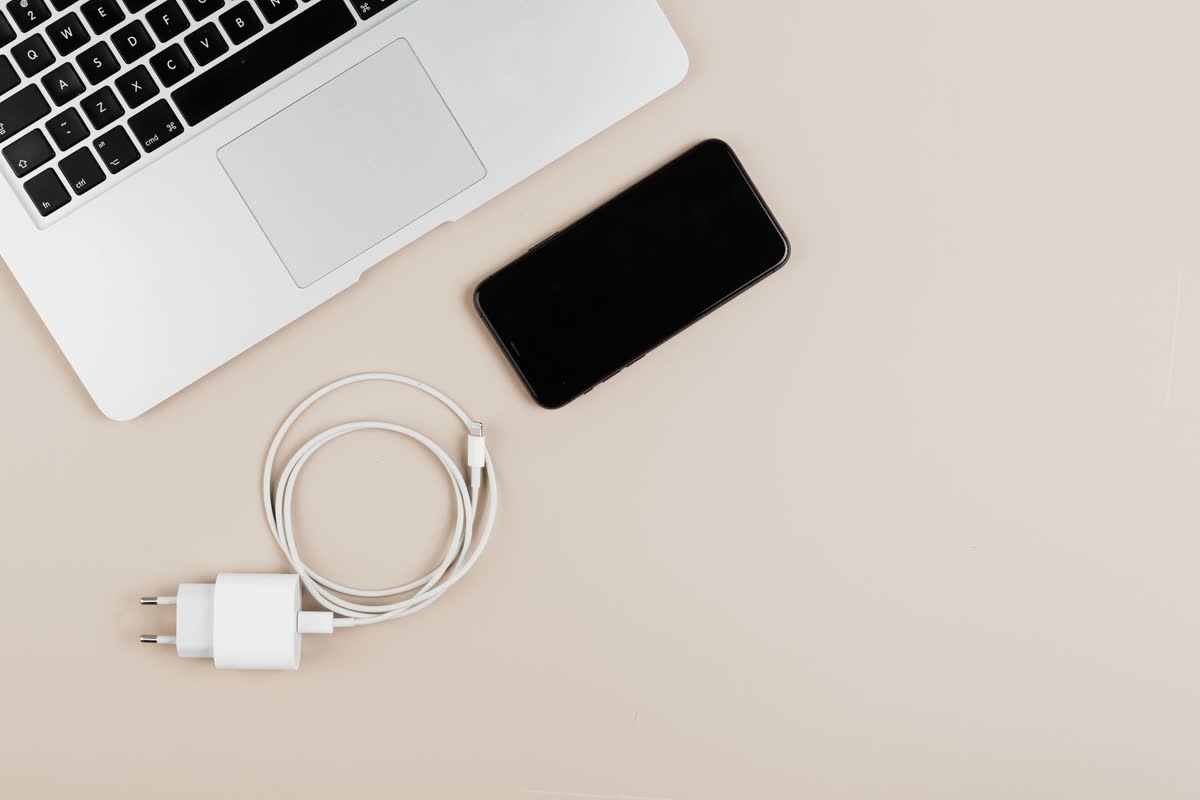 Una laptop, un teléfono y un cargador sobre un escritorio