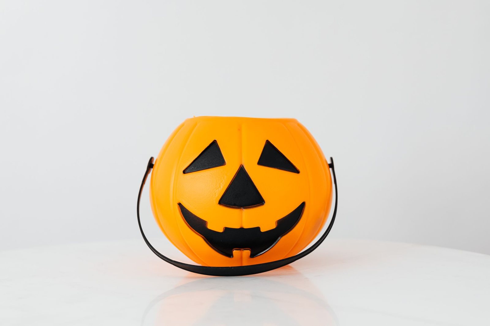 A jack-o-lantern candy pail on a plain background