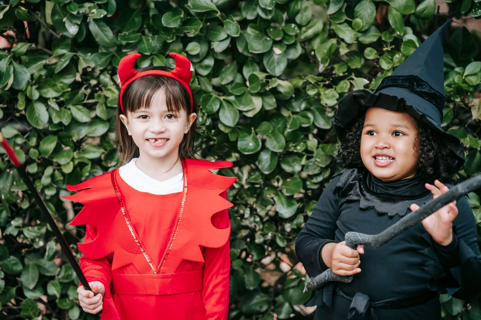 Dos niños con disfraces brillantes de Halloween sonriendo al aire libre