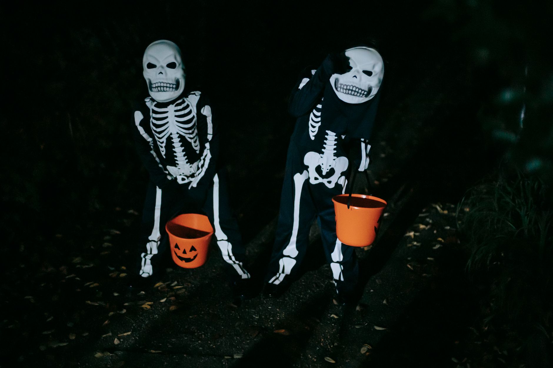 Dos niños con disfraces rojo brillante y de bruja sonriendo