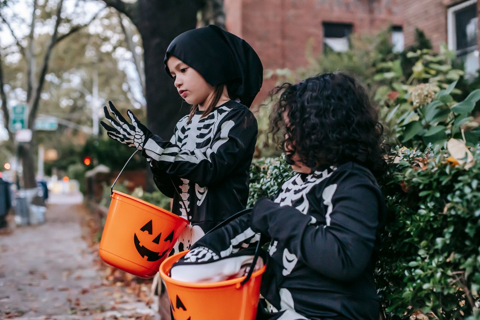Children in costumes trick-or-treating on a sidewalk at dusk