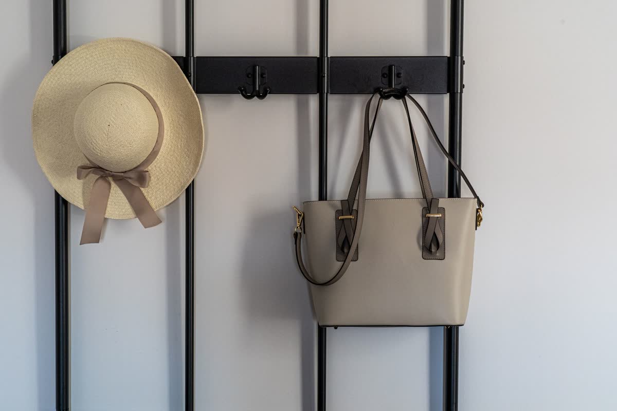 Bolsos y un sombrero colgados en ganchos de pared