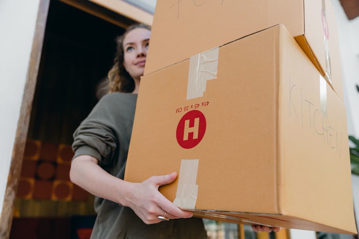 A student carrying a labeled moving box on move-in day