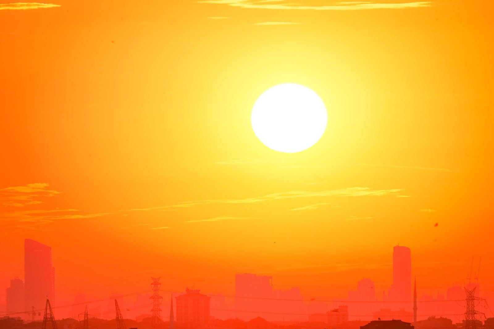 A blazing sun over a hazy city skyline during a heat wave