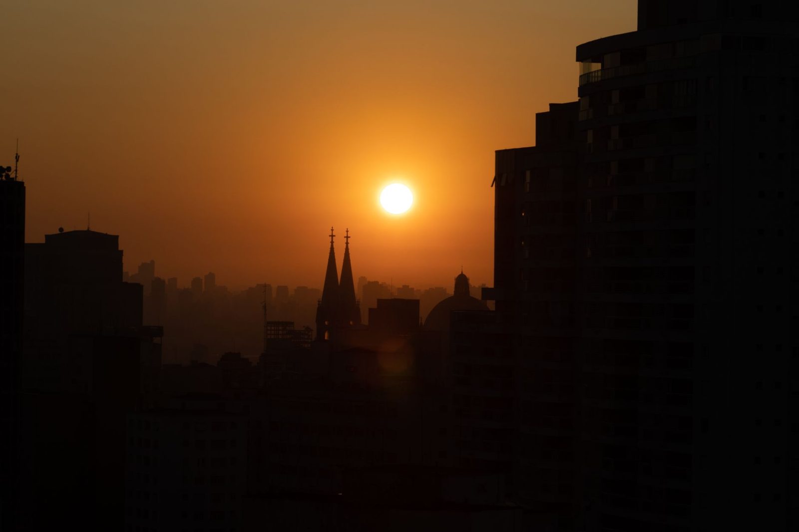 A hazy orange smoke-filled sky over a city skyline