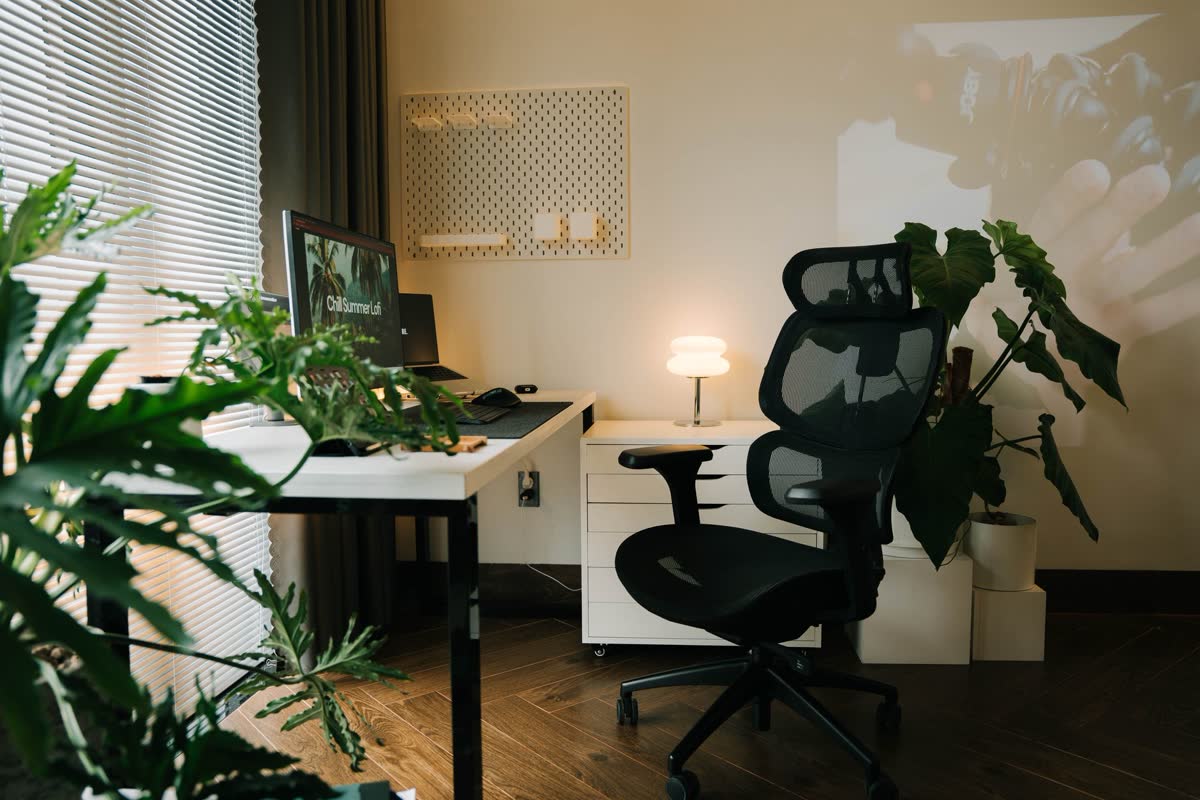 An ergonomic desk chair at a bright, plant-filled workspace