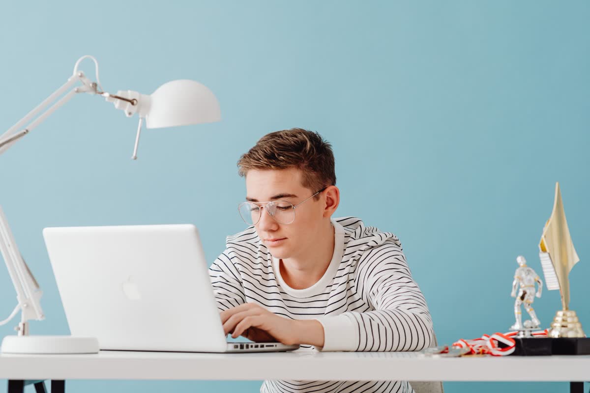 A student working at a laptop at a bright desk