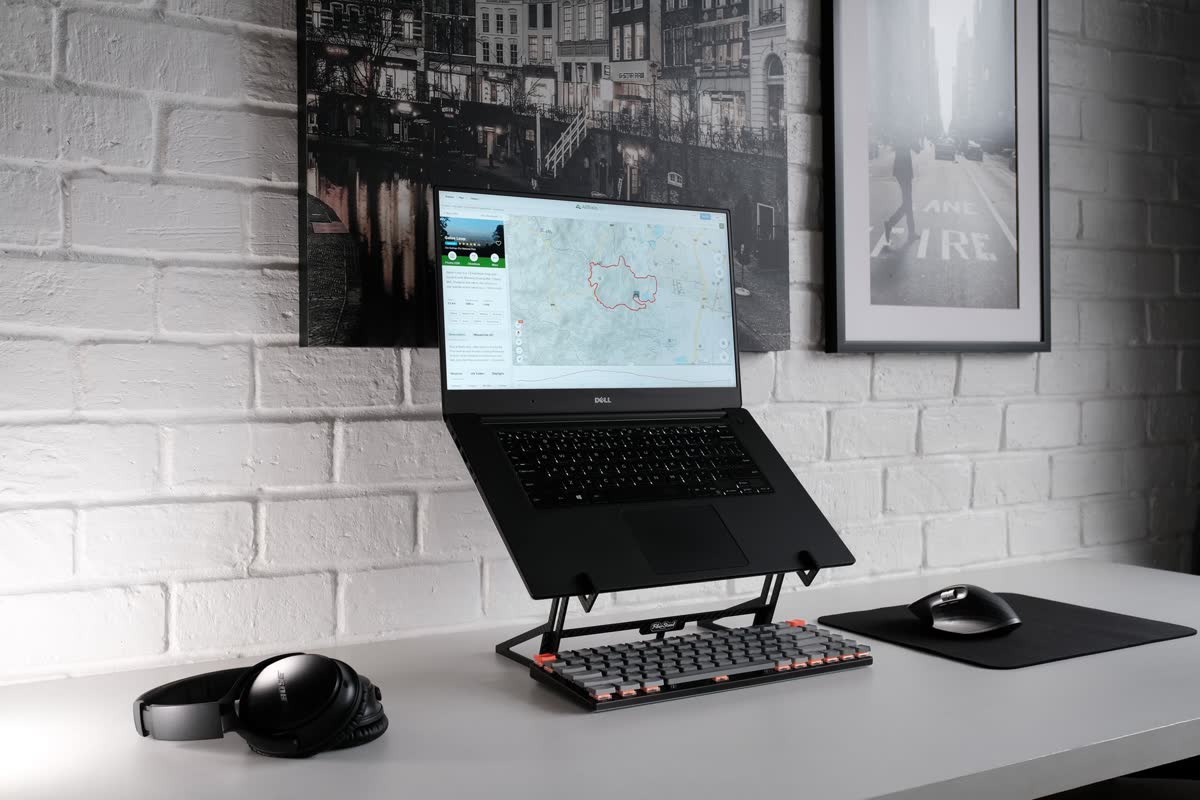 A laptop raised on a stand with a separate keyboard on a desk