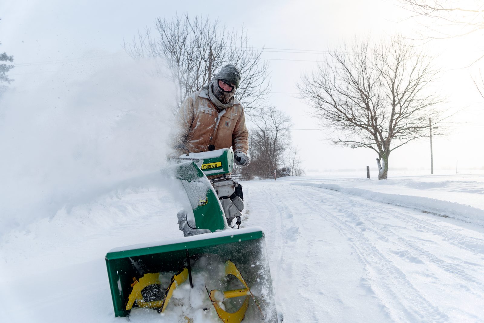 A person clearing a snowy driveway with a snow blower
